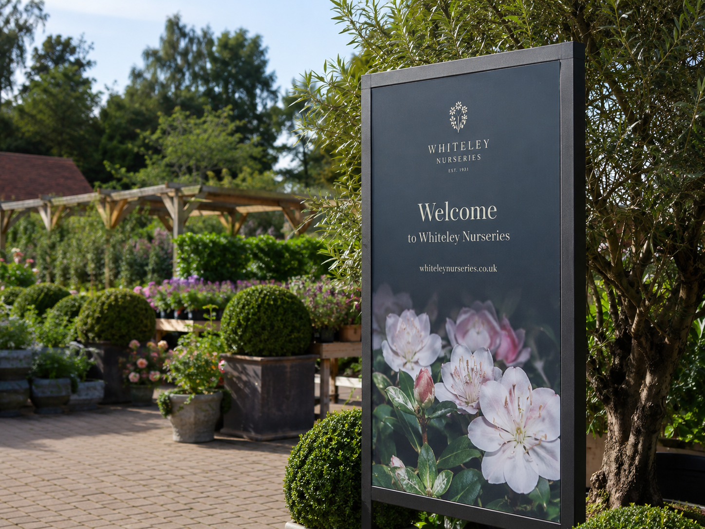 Welcome signage board for a nursery with floral design displayed in an outdoor garden setting